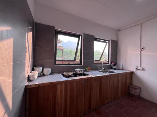 a kitchen with a sink and two windows at Zay Riverside House in Tả Van