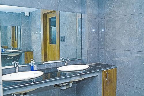 a bathroom with two sinks and a large mirror at Doon Sanskaram Hotel in Chūharpur
