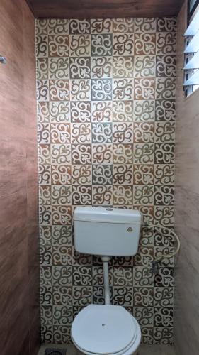 a bathroom with a toilet and a tile wall at Hotel M N Matheran in Matheran