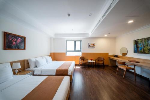a hotel room with two beds and a desk at WYNNE Hotel Nha Trang in Nha Trang