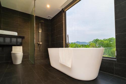 a bathroom with a large tub and a window at Karst Residence Phong Nha in Phong Nha