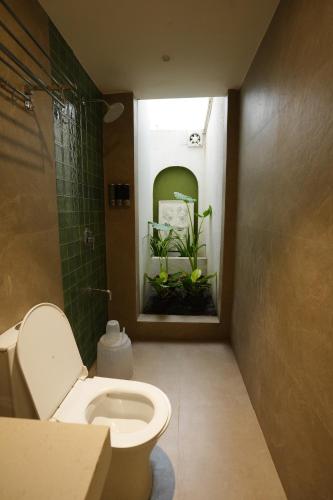 a bathroom with a toilet and a plant in a window at Bougainvillea in Nagaon