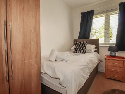 a bedroom with a bed with white sheets and a window at Treveline in Bodmin