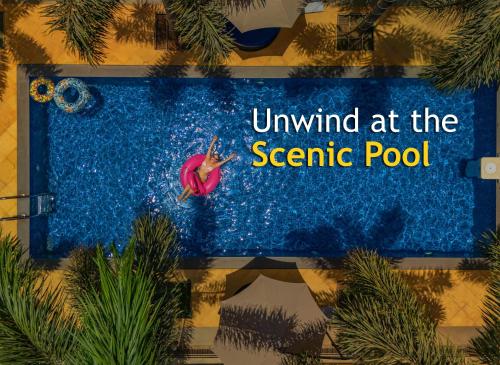a woman swimming in a pool with the text unwind at the scenic pool at Perfectstayz Premium Carnival Suites Near Candolim in Pilerne