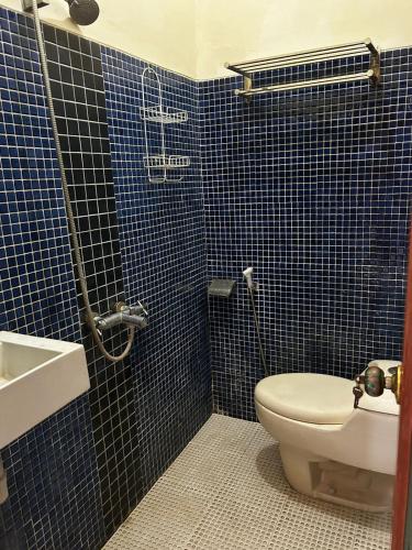 a blue tiled bathroom with a toilet and a sink at Villa Kecombrang in Salakan