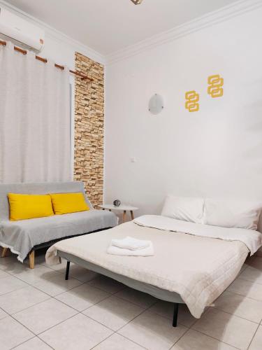 a white bedroom with two beds and a couch at Twins home in Ierapetra