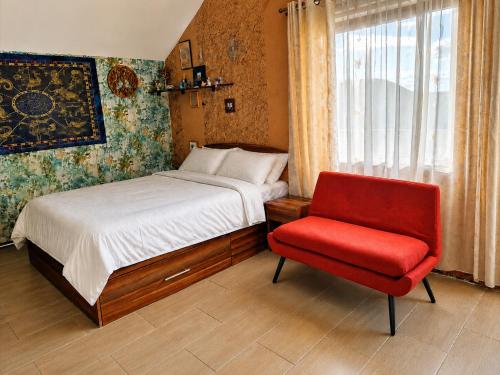 a bedroom with a bed and a red chair at Vis de Primăvară, vilă întreagă cu 4 dormitoare și vedere la lac in Limanu
