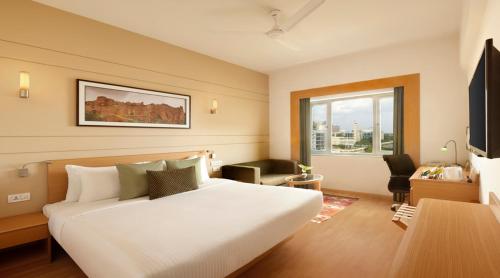 a bedroom with a large white bed and a window at Lemon Tree Hotel, Gachibowli, Hyderabad in Hyderabad