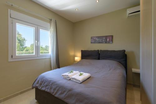 a bedroom with two towels on a bed with a window at Beach Villa Christina by PosarelliVillas in Acharavi
