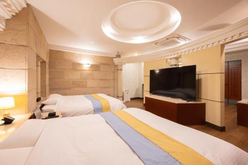 a hotel room with two beds and a flat screen tv at ホテルリノ in Kitakyushu