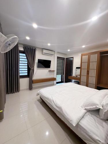 a bedroom with a large white bed and a television at SAM Homestay and Cafés in Thôn An Hòa