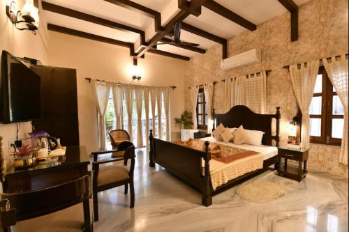a bedroom with a bed and a desk and a television at Eennra Oiitijhyya in Kolkata