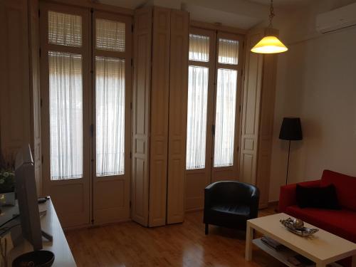 sala de estar con sofá rojo y algunas ventanas en Apartamento Montaño 4 Wifi gratis y 2 Baños, en Málaga