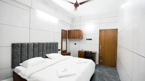a white bedroom with a large bed and a wooden cabinet at Sreebhadra Residency in Chavara