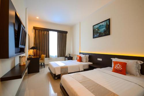 a hotel room with two beds and a television at Alqueby Hotel Bandung in Bandung