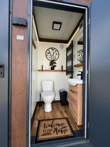 a bathroom with a toilet and a sign that reads welcome to our future at Glamping Hive by Stream in Víska