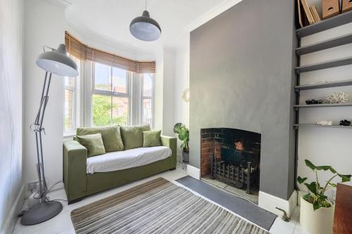 a living room with a green couch and a fireplace at Victorian Terrace near Uni sleeps 6 Garden in Reading