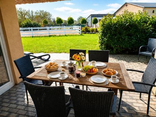 a wooden table with bowls of fruit on a patio at Reetdachhaus 6, inkl 2 Parkplätze in Fehmarn