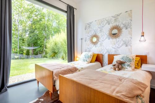 a bedroom with two beds and a large window at Sitelles Lodge Cube avec spa in Concarneau