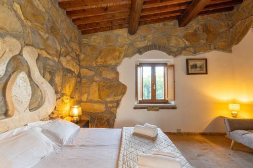 a stone walled bedroom with a bed and a window at Le Querciolaie with Geothermal Pool - by PosarelliVillas in Monteverdi Marittimo