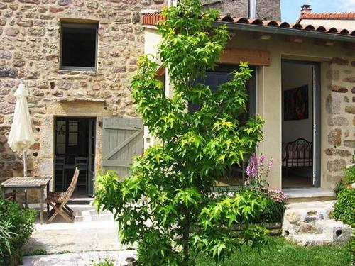 a tree in front of a house with a table at Gîte du Besset in Pradelles