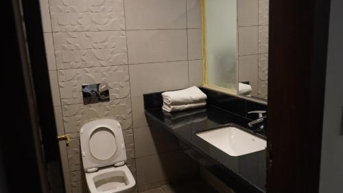 a bathroom with a sink and a toilet and a mirror at The King's Hotel in Tuticorin