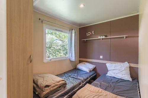 a room with two beds and a window at Mobil-home - Le 147 aux Iscles in La Roque-dʼAnthéron