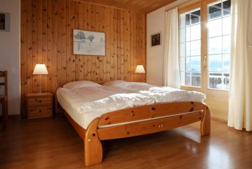 a bedroom with a bed with a wooden wall at Chalet Bühlweidli by Ferienlenk in Lenk