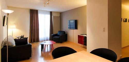 een woonkamer met een bank, een tafel en een stoel bij Les Negociants in Vevey