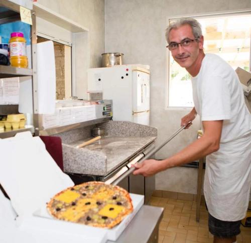 a man standing in a kitchen with a pizza at Camping 3 étoiles - Piscine - ccbgaci in Illiers
