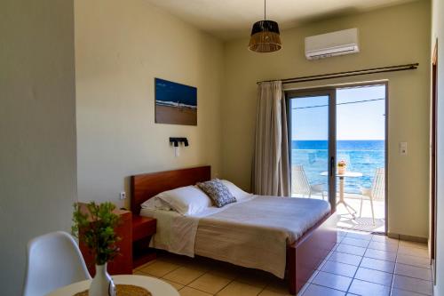 a bedroom with a bed and a view of the ocean at Skinos Apartments in Plakias