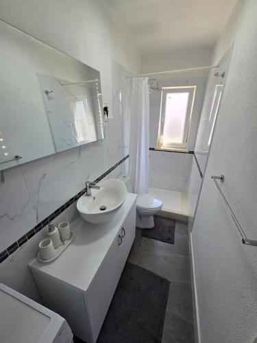 a white bathroom with a sink and a toilet at Seba Apartments in Korčula