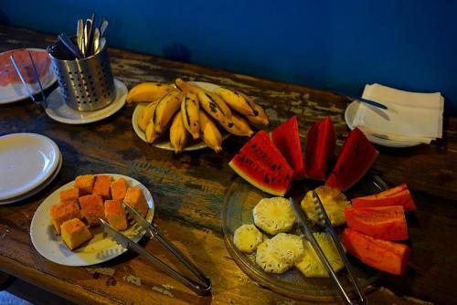 una mesa de madera con platos de fruta y plátanos en Hostel Galeria 13, en Salvador