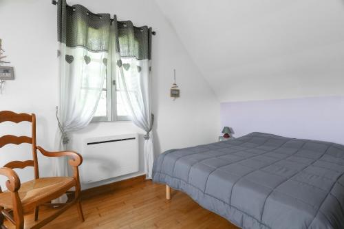 a bedroom with a bed and a chair and a window at Gîte Lilas de mer in Ponthoile