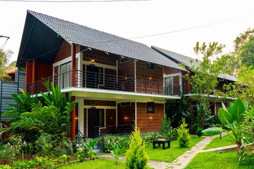 a house with a balcony and a yard at Avocado Cottages by Alaya Stays, Coorg in Suntikoppa