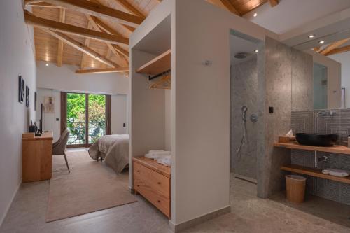 a bathroom with a shower and a bedroom at Valeni Boutique Hotel & Spa in Portaria