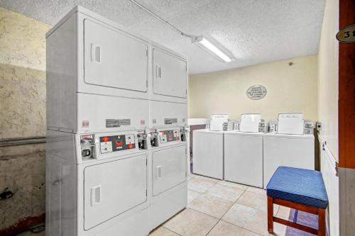 a kitchen with white appliances and a blue stool at Carolinian Beach Resort in Myrtle Beach