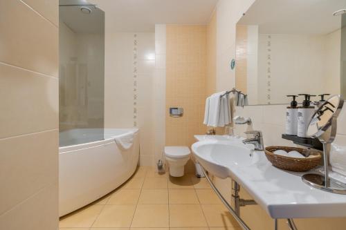 a bathroom with two sinks and a tub and a toilet at Hotel Pušyno Namai in Tirkšliai