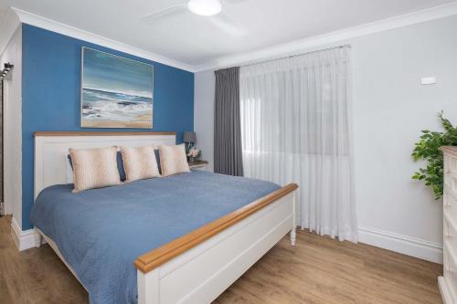 a blue bedroom with a bed and a window at BJ Mick's Lakefront Apartment in Forster