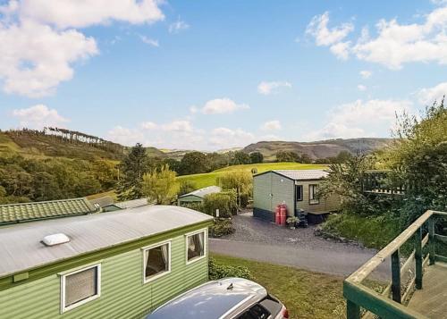 a green caravan with a car parked in front of it at Garth Holiday Park in Machynlleth