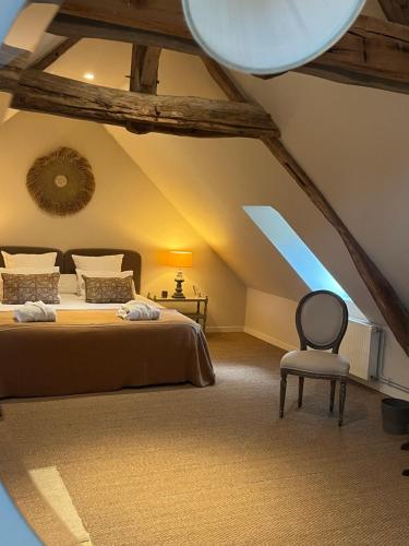a attic bedroom with a bed and a chair at Chambres d'Aumont in Aumont