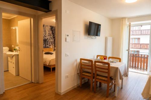 a dining room with a table and chairs and a bedroom at Erica in Folgaria
