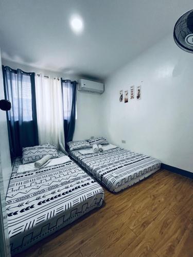 two beds in a room with wooden floors at Khaleejay Transient House in Calapan