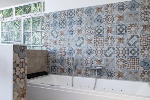 a bath tub in a bathroom with a tile wall at Suite Cotinga, balneo, bien-être, Parc des Oiseaux in Villars-les-Dombes