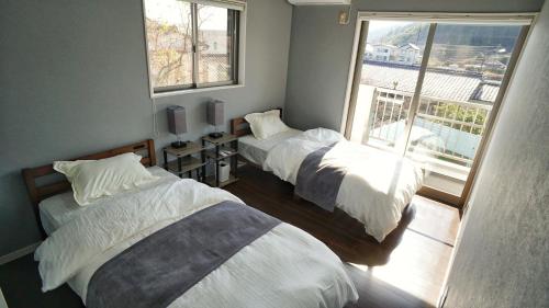 a bedroom with two beds and a balcony at Sauna villa uchiumi in Uchiumi