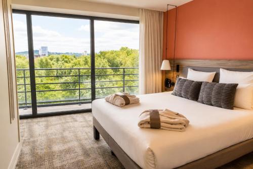 a bedroom with a large bed with a large window at Novotel Suites Rouen Normandie in Rouen