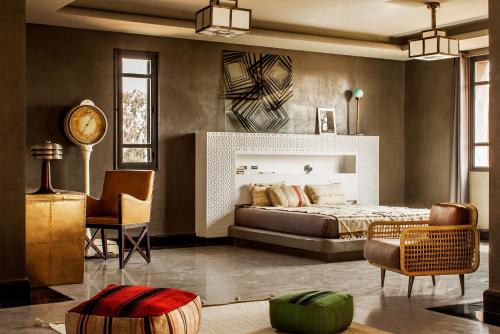 una camera con letto, sedia e orologio di Fellah Hotel a Marrakech