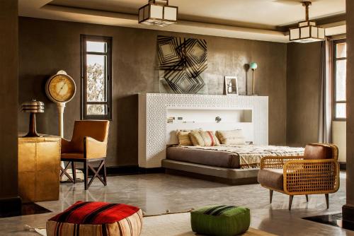 a bedroom with a bed and a chair and a clock at Fellah Hotel in Marrakesh