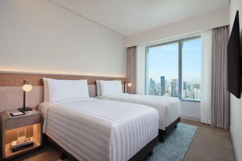a hotel room with two beds and a large window at PARKROYAL Serviced Suites Jakarta in Jakarta