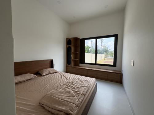 a bedroom with a large bed and a window at Cuchi Downtown in Xóm Bến Cỏ
